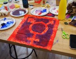 A blue combined unicode symbol for male and female screen printed on red fabric