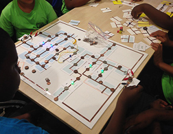 A group of students site with a circuit game board at the center