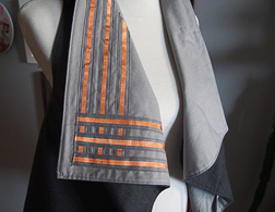 The top of a dress form that donning a gray vest with a long triangular collar containing a 3x3 matrix of copper fabric traces